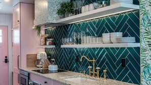 Una cocina con armarios rosados, un salpicadero verde tipo espiga y una encimera de granito.