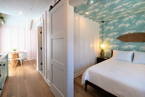 Un dormitorio con una cama, un escritorio con una silla y una pared con un diseño de olas.