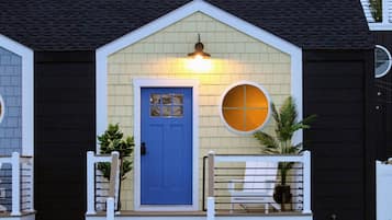 A house with a blue door, a small porch with a railing, and a round window above the door.