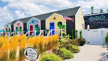 A coastal-themed building with multiple colorful structures, a flag, and a sign indicating 'The Coastal Quad.'