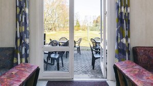 Ein Zimmer mit einer Schiebetür und Zugang zu einem Sitzbereich im Freien mit Stühlen und einem Tisch.