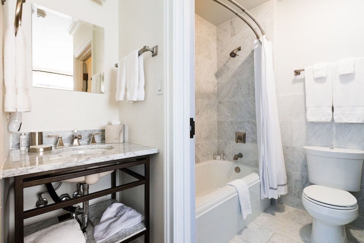 A modern bathroom with a marble sink, a bathtub, and a toilet.