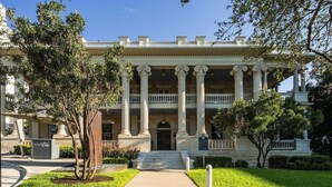 A hotel with a grand entrance, columns, and a well-maintained lawn.