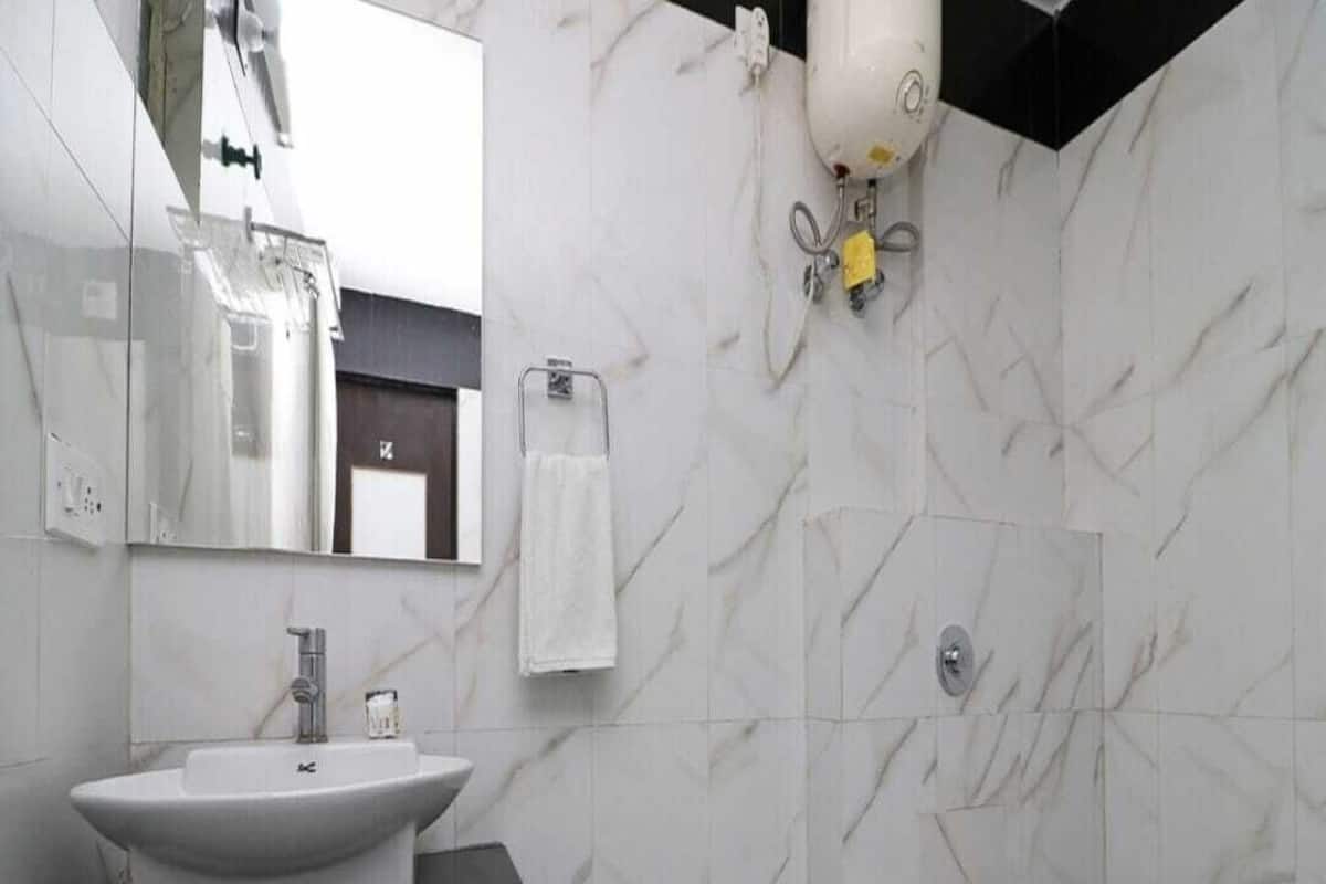 A modern bathroom with a white sink, black countertop, white toilet, and a shower area.