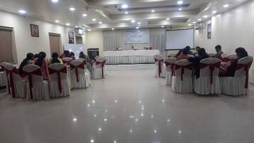 Un salón de conferencias con filas de sillas y un escenario.