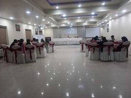 Un salón de conferencias con filas de sillas y un escenario.