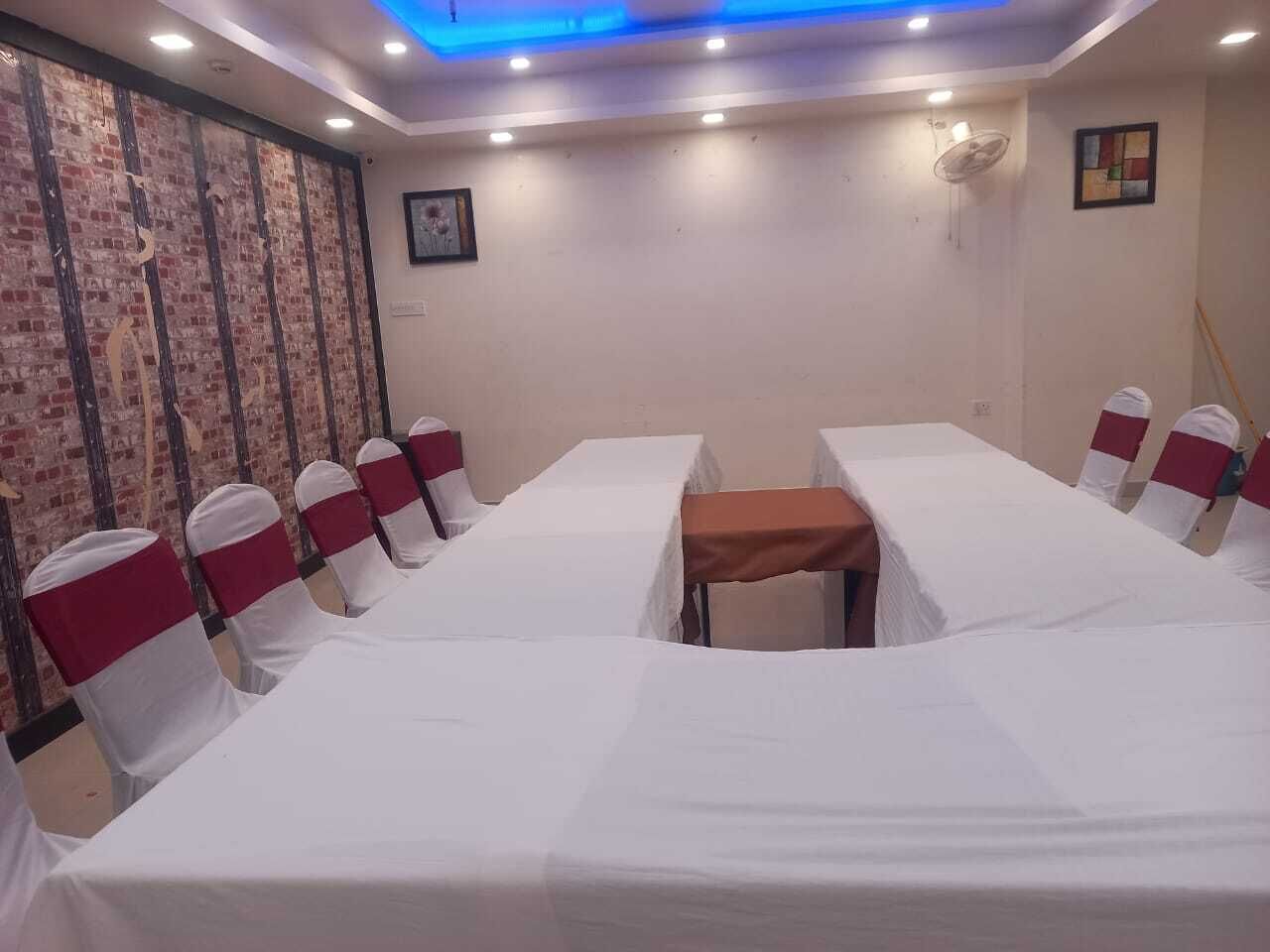 A conference room with a long table, white chairs with red sashes, and a ceiling light fixture.