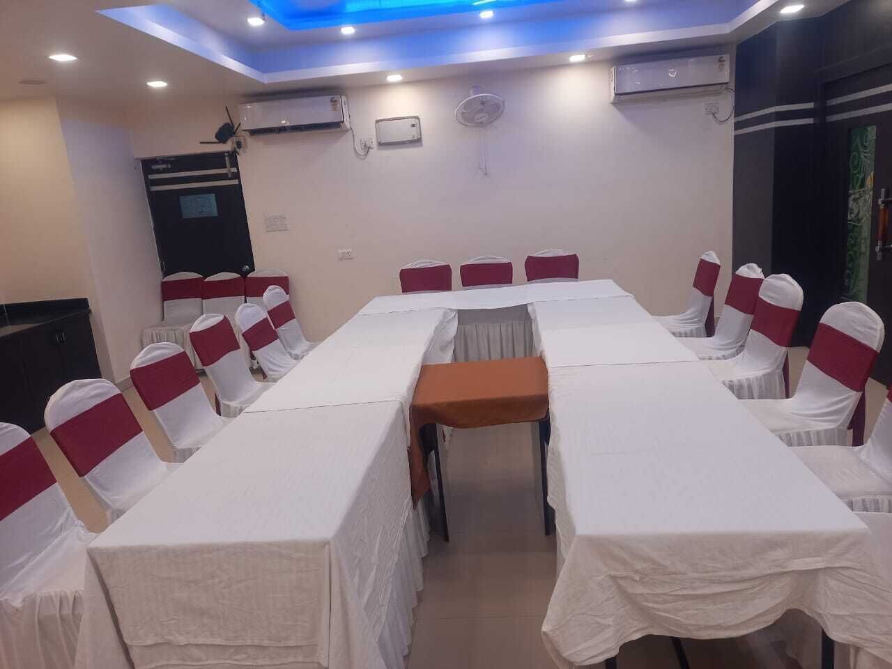 Ein Konferenzraum mit einem langen Tisch, Stühlen mit weiß-roten Bändern und Deckenleuchten.