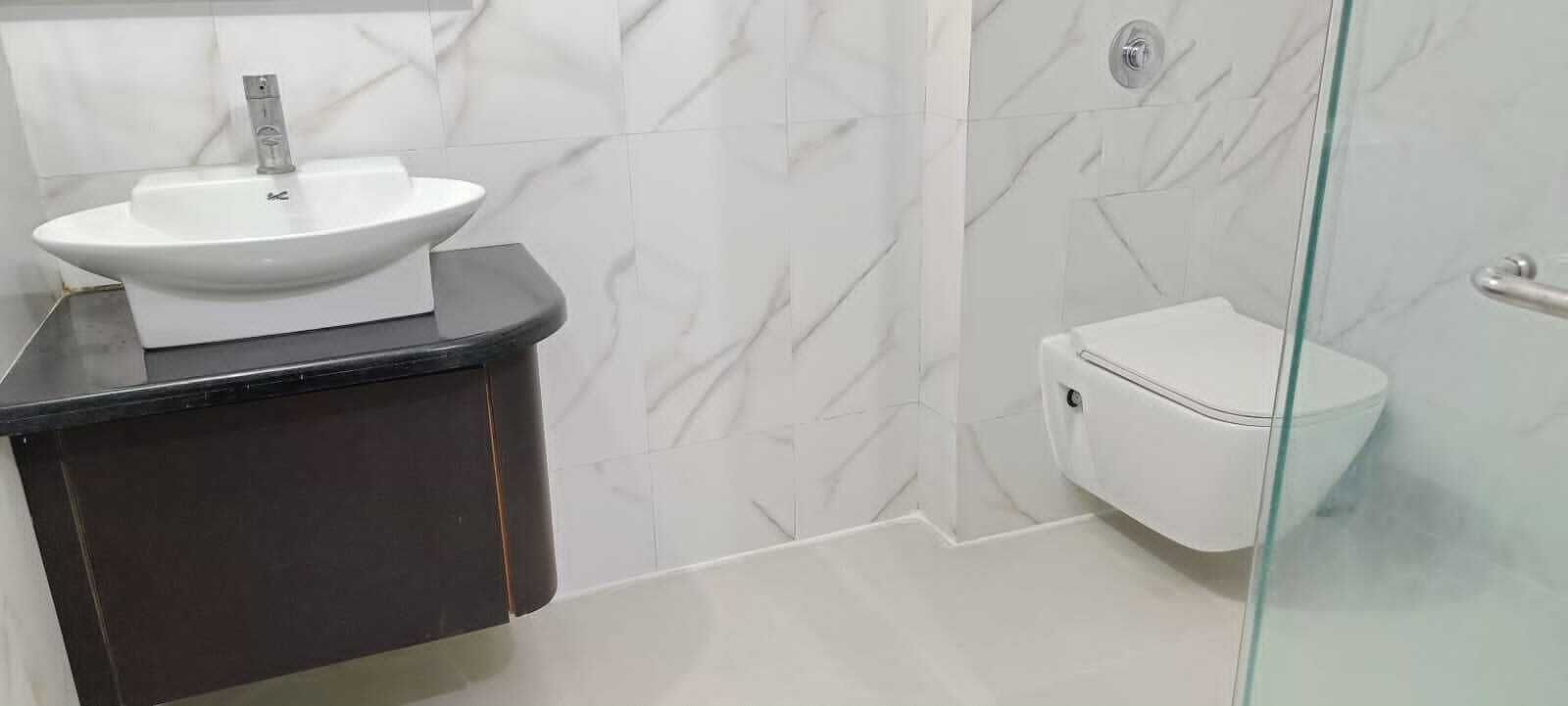 Een badkamer met een wit wastafel, toilet en een douchecabine met glazen wanden.