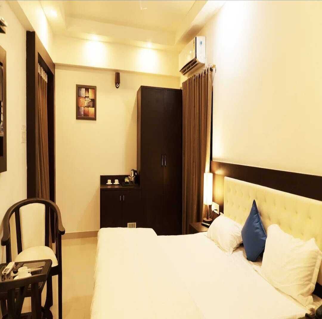 A hotel room with a bed, a wardrobe, a desk with a lamp, and a chair.
