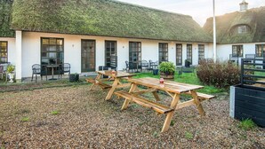 A building with a thatched roof, numbered rooms, outdoor seating, and a gravel courtyard. - 2 Person Holiday Park Home in Fano (Fano)