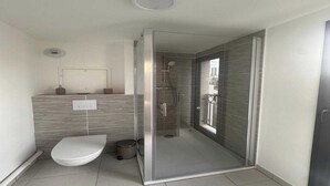 A modern bathroom with a glass-enclosed shower, a toilet, and a sink with a mirror. - Elegant Appt - 3BDR/8P - Near Paris & La Défense (Suresnes)