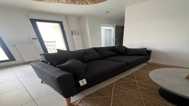 A modern living room with a black sofa, a round coffee table, and a patterned rug.