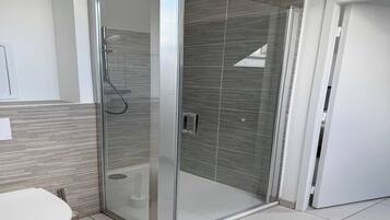 Une salle de bain moderne avec une douche à parois de verre, des toilettes et un lavabo blanc.