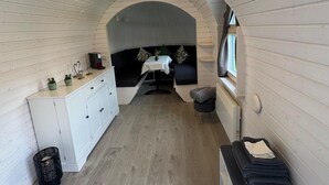 Ein kompakter, moderner Raum mit Holzboden, einem weißen Schrank, einem kleinen Tisch mit Stuhl und einem Fenster.