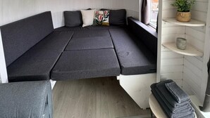 Ein gemütliches Zimmer mit gewölbter Decke, einer Couch, einem kleinen Tisch und Regalen mit Pflanzen.