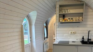 Eine kompakte Küche mit integrierter Kochinsel, weißen Schränken und einem kleinen Fenster.