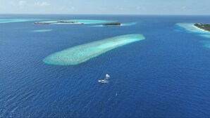 An aerial view of a coastal area with clear blue waters, several small islands, and a boat in the water. - Charming 2-bedroom bed & breakfast in lovely Felidhoo with AC (Felidhoo)