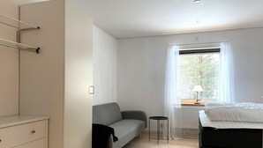 A modern bedroom with a bed, a gray sofa, a small table, and a dresser. - 3 Person Holiday Park Home in Orsa (Orsa)