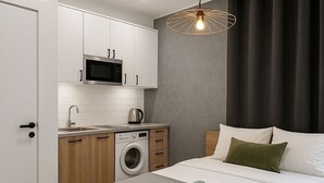 A modern bedroom with a bed, a washing machine, and a kitchenette. - Charming apartment for seasonal rental (Madrid)
