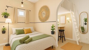A bedroom with a bed, a desk, a chair, a mirror, and a staircase. - Charming apartment for seasonal rental (Madrid)