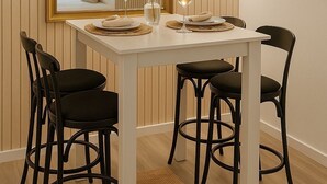 A dining area with a white table set for four, black chairs, a gold-framed mirror, and a wall-mounted lamp. - Charming apartment for seasonal rental (Madrid)