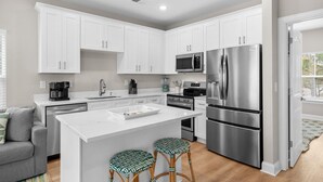A modern kitchen with white cabinets, stainless steel appliances, and a central island with stools.