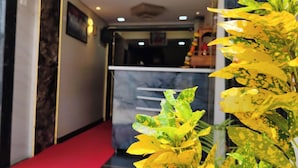 A hotel reception area with a red carpet leading to a counter. - Hotel Sai Samrat Inn (Panvel)