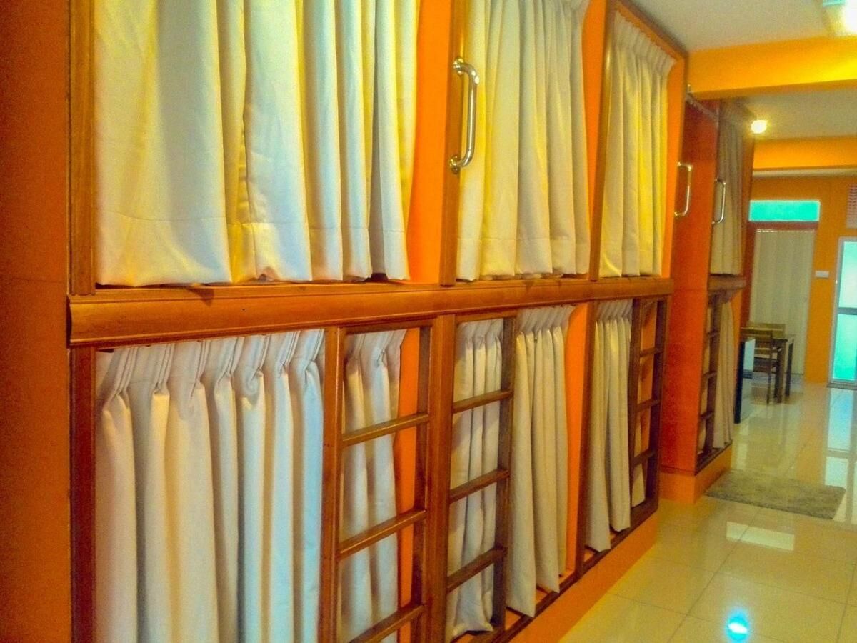 Un pasillo con pared de paneles de madera, cortinas blancas y una puerta con picaporte.