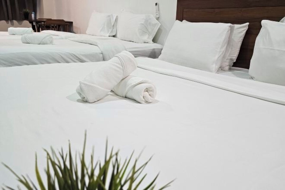 A hotel room with neatly made beds, white linens, and a wooden headboard.