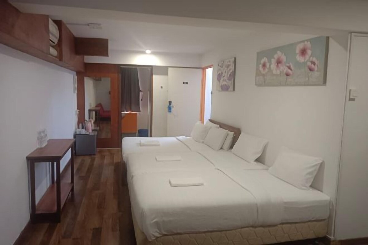 A bedroom with a large bed, a small table, and a mirror.