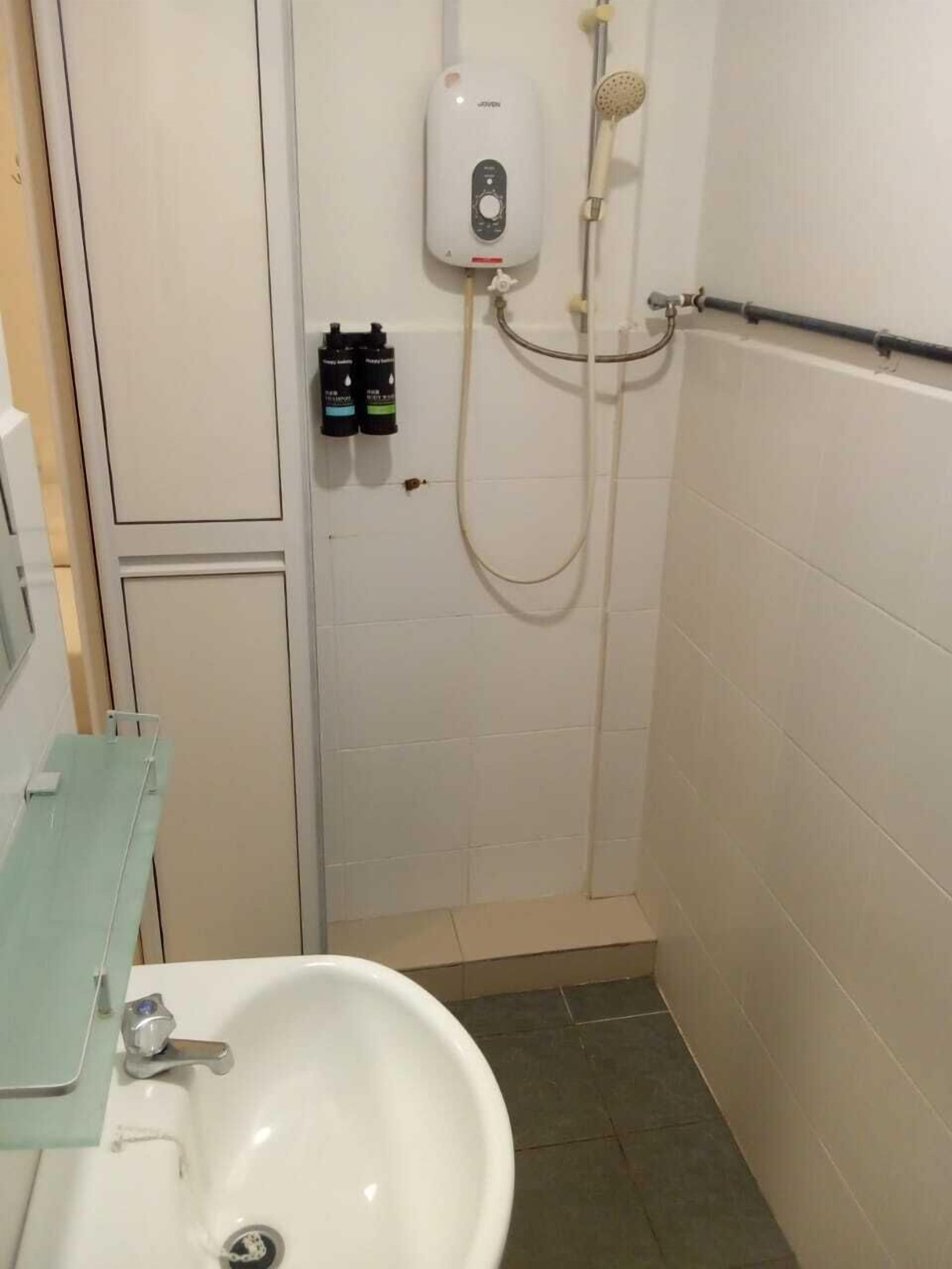 A bathroom with a white sink, a handheld showerhead, and a wall-mounted control panel.