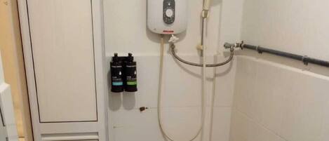 A bathroom with a white sink, a handheld showerhead, and a wall-mounted control panel.