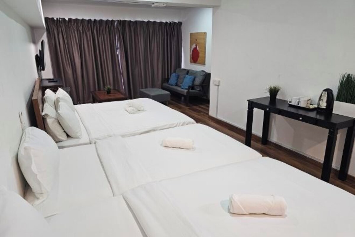 A hotel room with two beds, a sofa, a small table, and a TV.