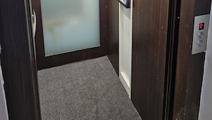 An elevator with wooden walls, a control panel, and a carpeted floor. - Heliconia by Treebridge (George Town)