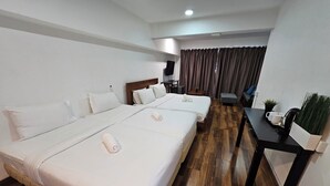 A hotel room with two beds, a desk, a chair, a TV, and a window with curtains. - Heliconia by Treebridge (George Town)