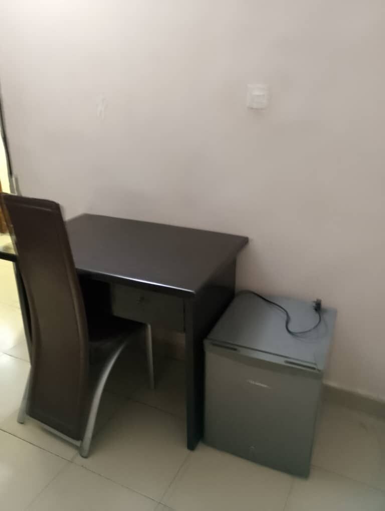 A small room with a dark wooden table and a chair, a small grey cabinet, and a tiled floor.
