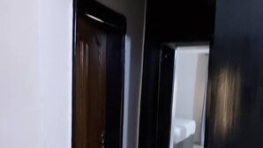 A hallway with a wooden door on the left and a black door on the right. - Morada Hotels (Lagos)