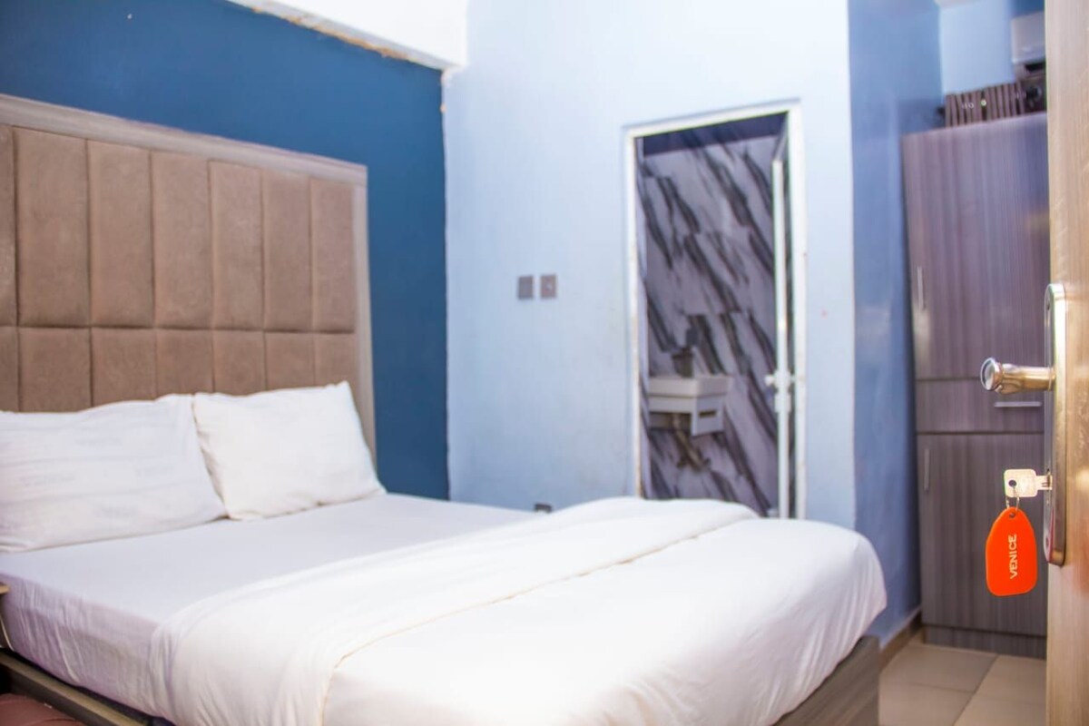 A bedroom with a bed, a wardrobe, and a door with a marble pattern.