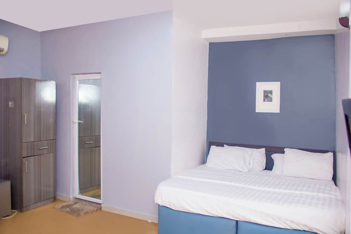 Un dormitorio con cama, armario y puerta que da a un baño.