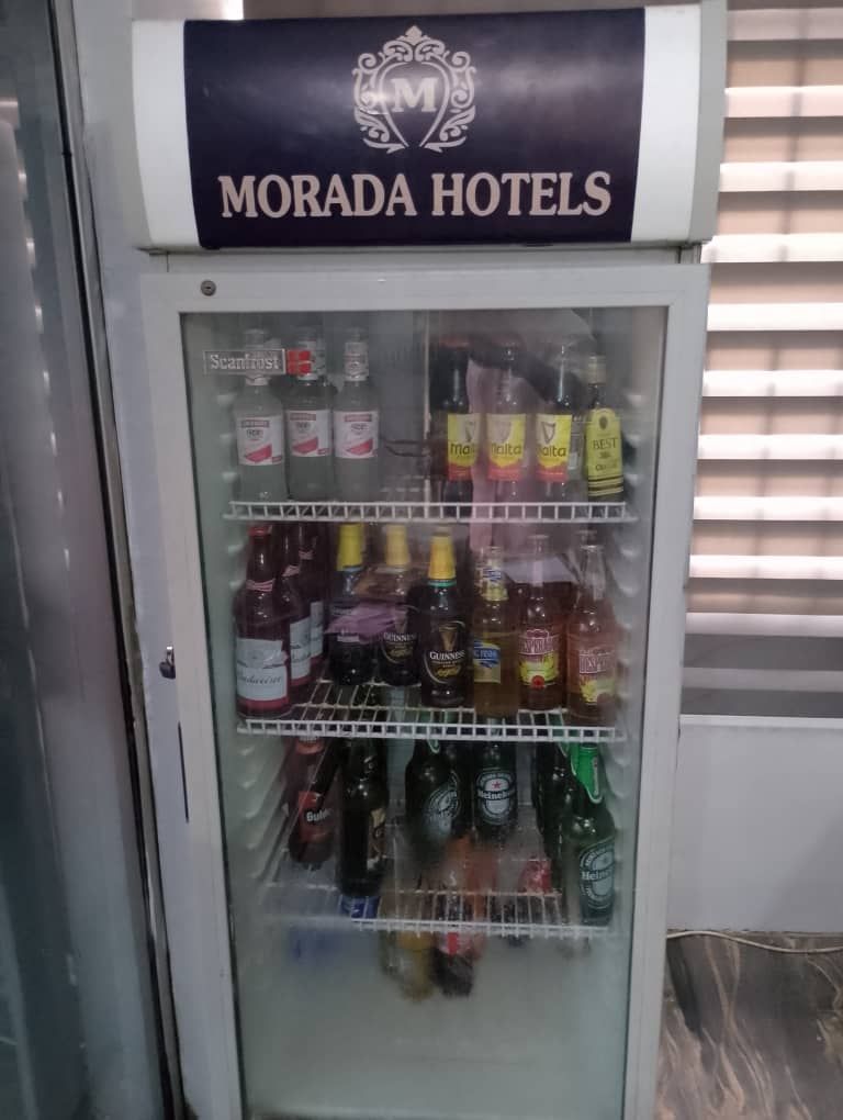 A minibar with a Morada Hotels sign above it, containing various alcoholic beverages.
