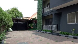 A courtyard with a paved ground, a gated entrance, and a building with a balcony. - Morada Hotels (Lagos)