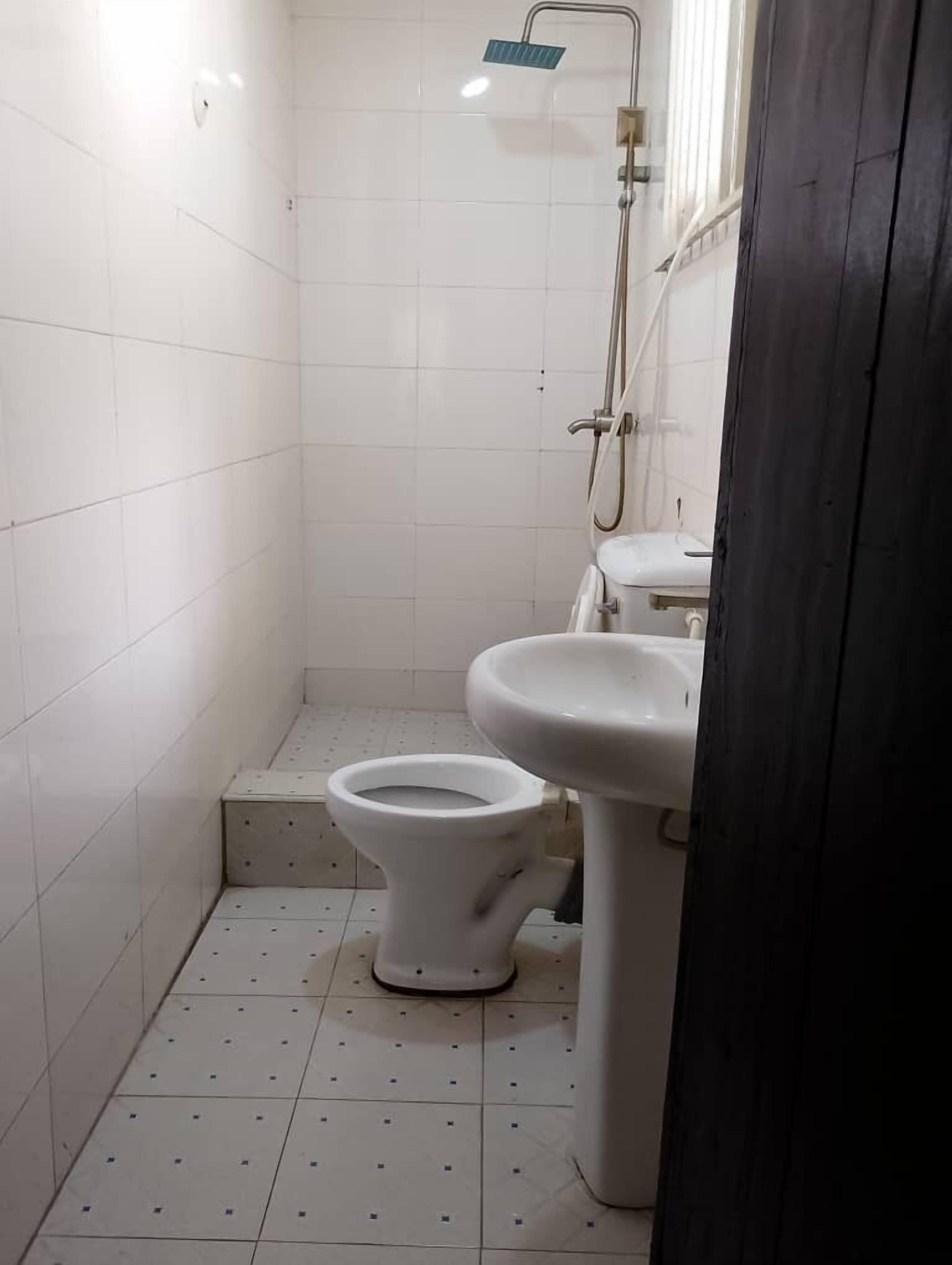 Un baño pequeño con azulejos, un inodoro, un lavamanos y una ducha.