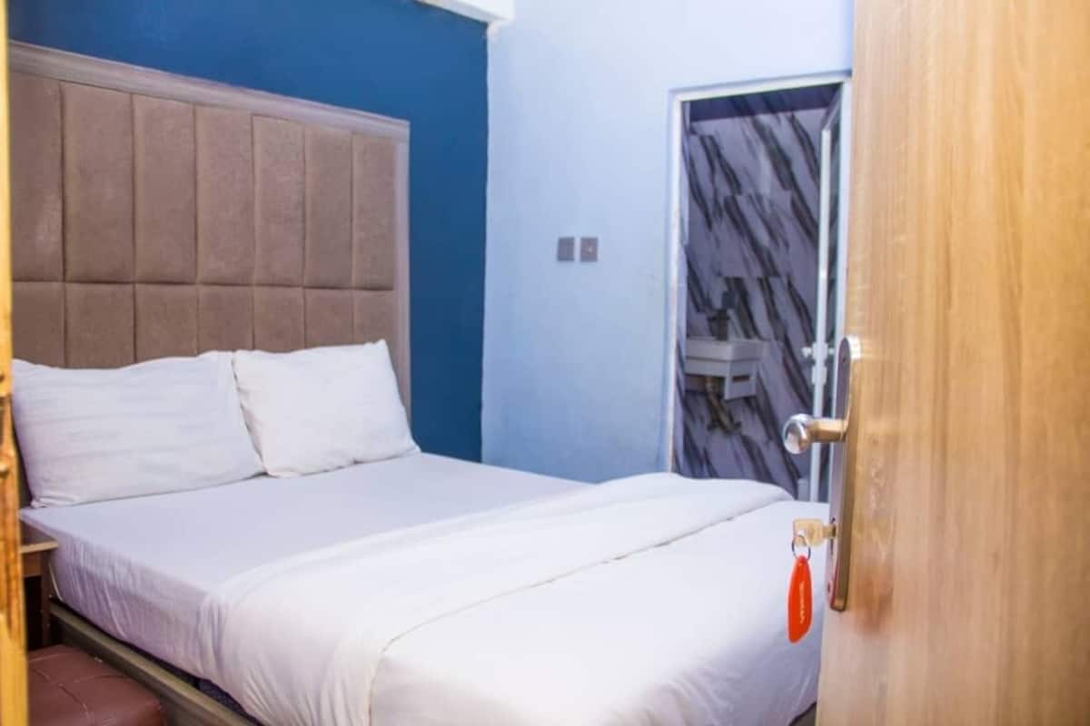 Un dormitorio con cama, cabecera, una puerta y una pared con diseño.