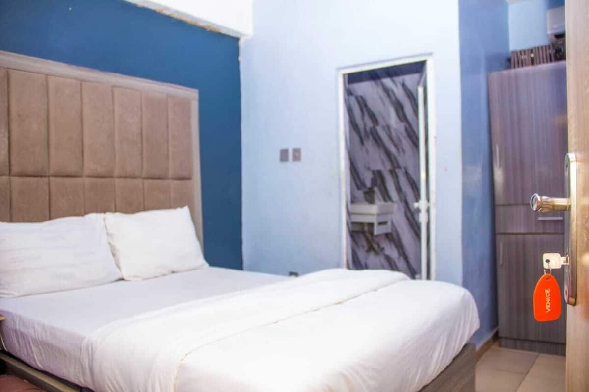 Un dormitorio con cama, armario y puerta con diseño de mármol.