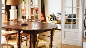 A dining area with a wooden table and chairs, a lamp, and a view through a glass door.