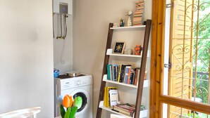 Un lavadero con lavadora, secadora y una repisa de madera con libros y objetos decorativos.