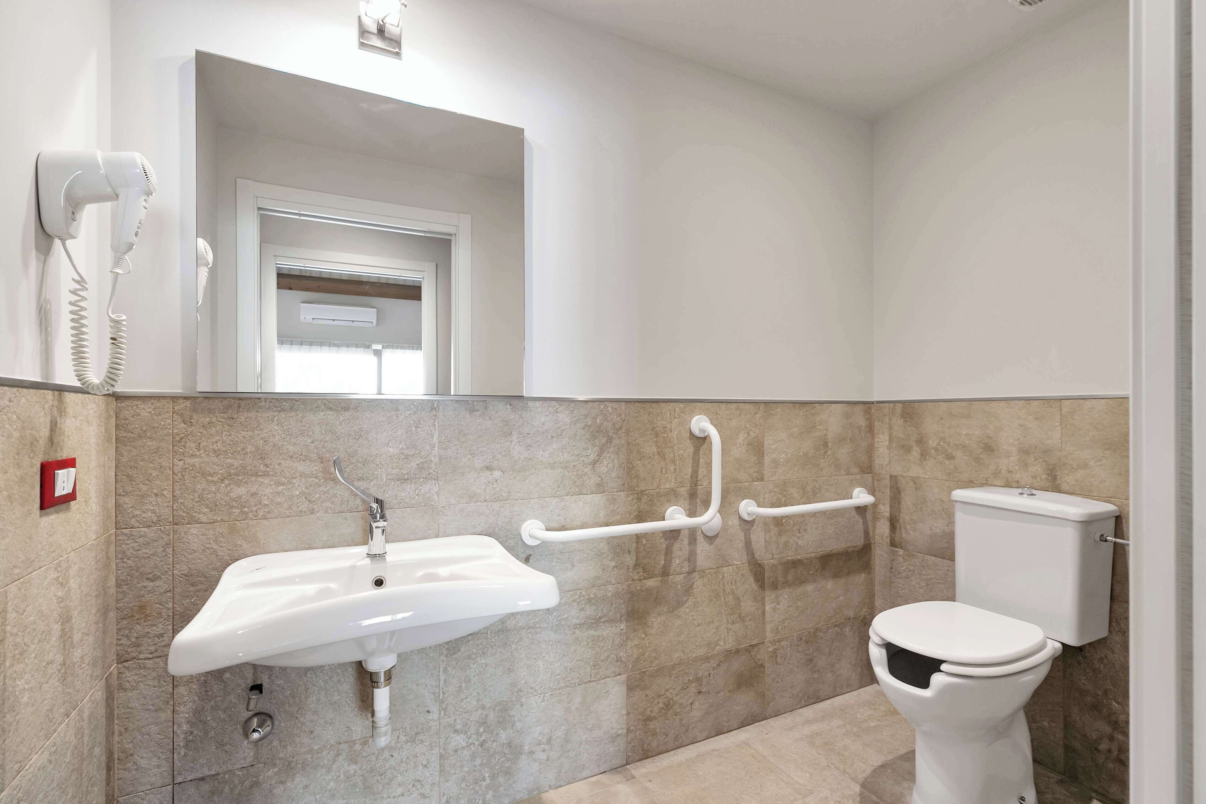 A bathroom with a sink, toilet, and hand dryer.