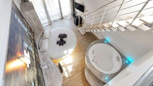 A modern hotel room with a large bed, a bathtub, a TV, and a staircase. - Suite A Tema (Milan)