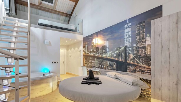 A bedroom with a cityscape mural, a round bed, a staircase, and a built-in bench. - Suite A Tema (Milan)